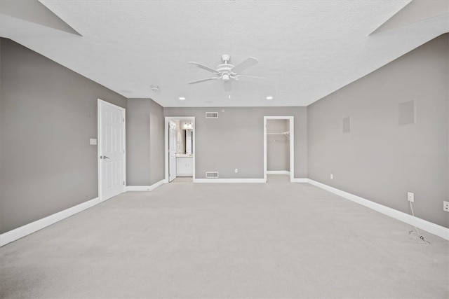 empty room with a textured ceiling, light colored carpet, and ceiling fan