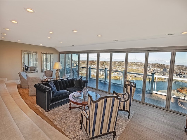 living room featuring a wealth of natural light, a water view, and light hardwood / wood-style flooring