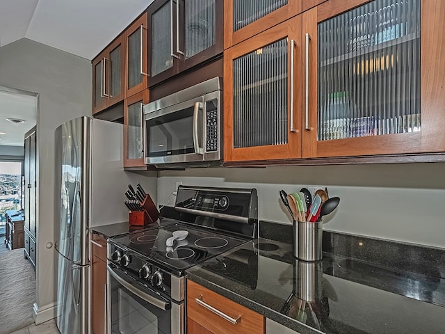 kitchen featuring dark stone countertops, lofted ceiling, and stainless steel appliances