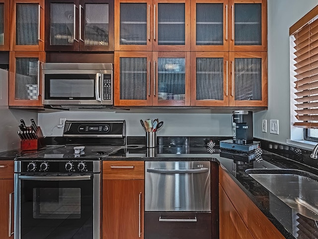 kitchen featuring dark stone counters, appliances with stainless steel finishes, and sink