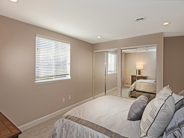 bedroom featuring light carpet and multiple closets