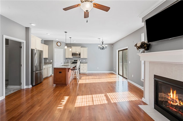 kitchen with appliances with stainless steel finishes, light stone counters, a breakfast bar, hanging light fixtures, and an island with sink