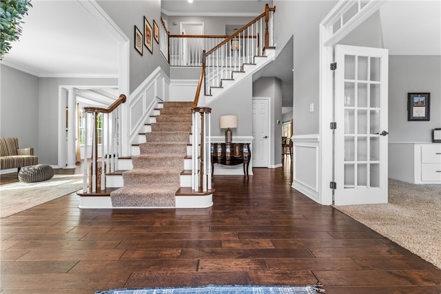 entrance foyer with dark wood-type flooring, a high ceiling, and ornamental molding