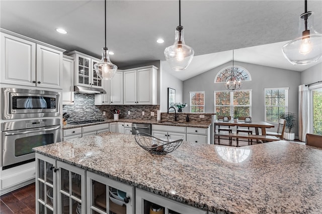 kitchen with lofted ceiling, light stone counters, hanging light fixtures, sink, and dark hardwood / wood-style floors