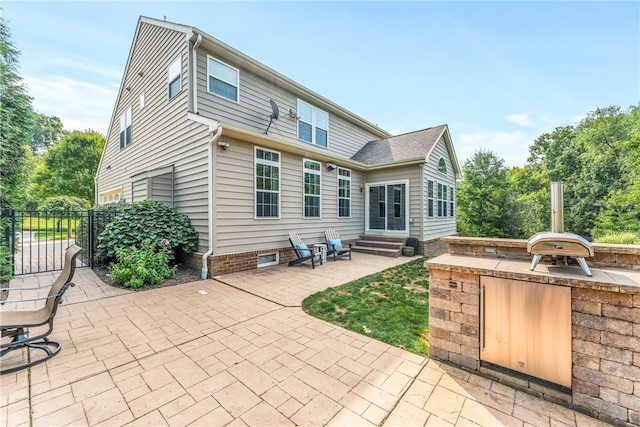 rear view of property featuring an outdoor kitchen and a patio