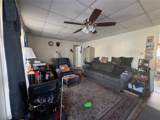 living room featuring a drop ceiling, wood-type flooring, and ceiling fan