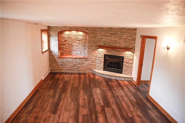 unfurnished living room featuring a stone fireplace, a textured ceiling, dark hardwood / wood-style floors, and a baseboard heating unit