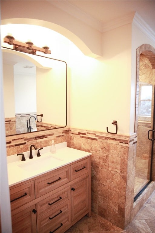 bathroom with vanity, tile walls, a shower with door, and crown molding