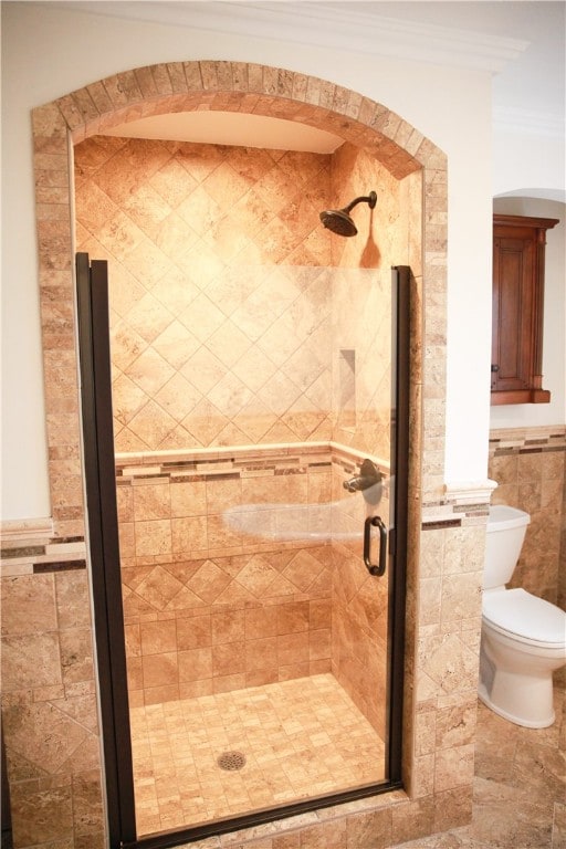 bathroom featuring crown molding, toilet, an enclosed shower, and tile walls