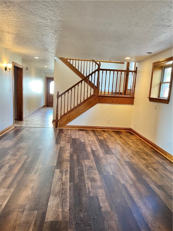 unfurnished living room featuring dark hardwood / wood-style flooring and a textured ceiling