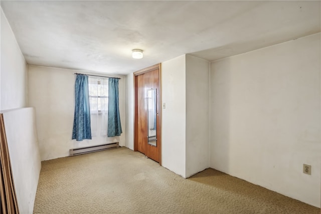 empty room featuring a baseboard heating unit and light carpet