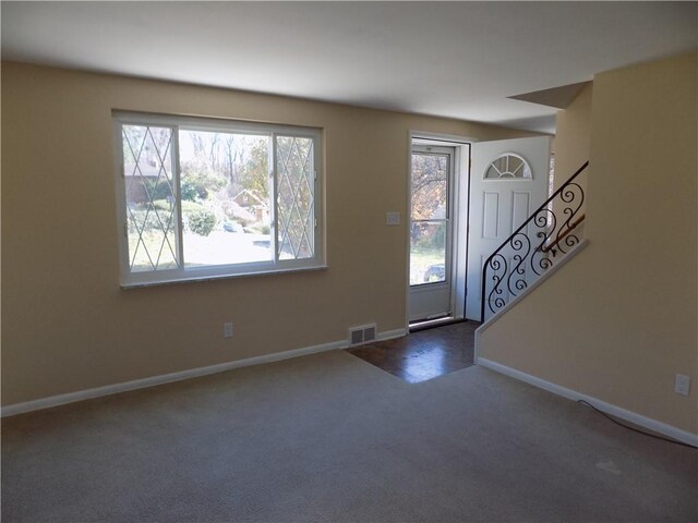 entrance foyer featuring a wealth of natural light and dark carpet