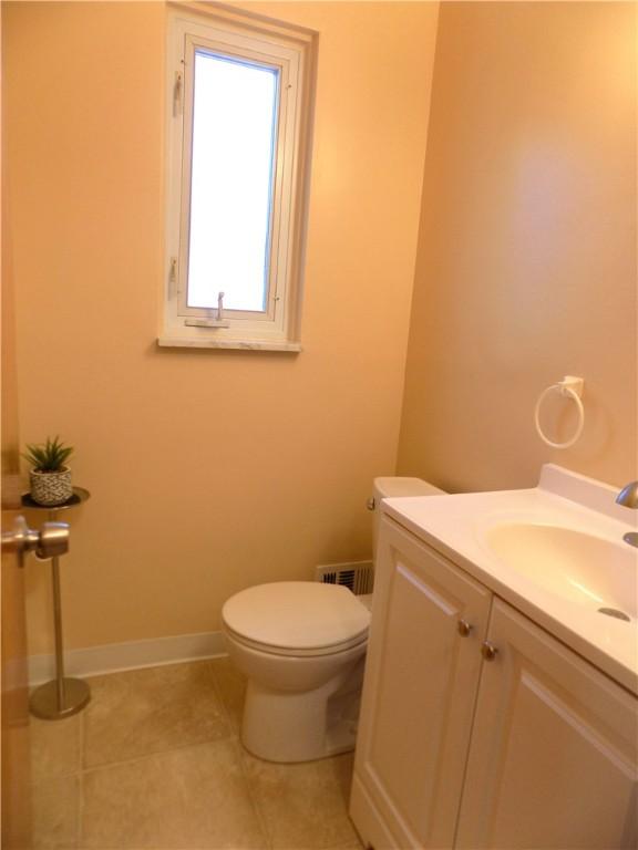 bathroom with toilet, vanity, and tile patterned floors