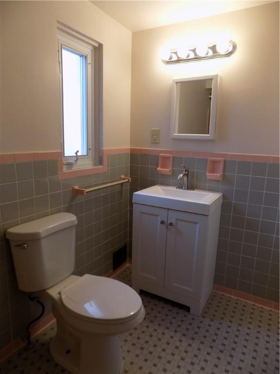 bathroom featuring tile patterned flooring, vanity, toilet, and tile walls