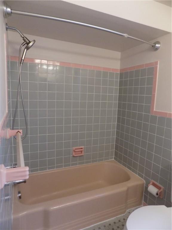 bathroom featuring toilet and tiled shower / bath