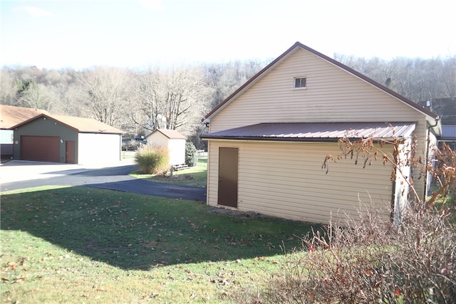 view of side of property featuring a garage, an outdoor structure, and a lawn