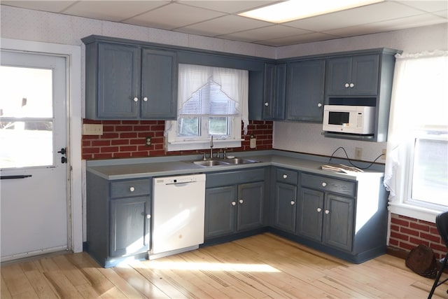 kitchen featuring a paneled ceiling, white appliances, sink, and light hardwood / wood-style floors