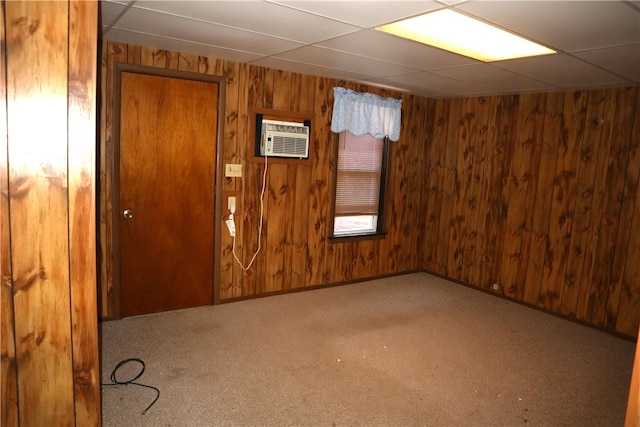 empty room featuring a wall unit AC, a paneled ceiling, and wood walls