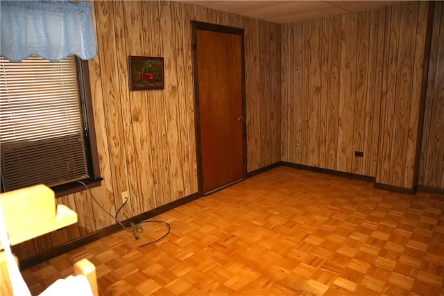 spare room featuring wood walls and light parquet flooring