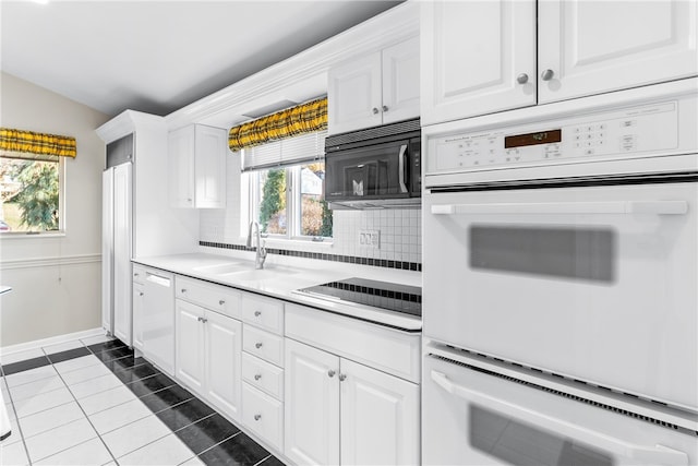 kitchen with tasteful backsplash, tile patterned floors, white cabinetry, sink, and white appliances