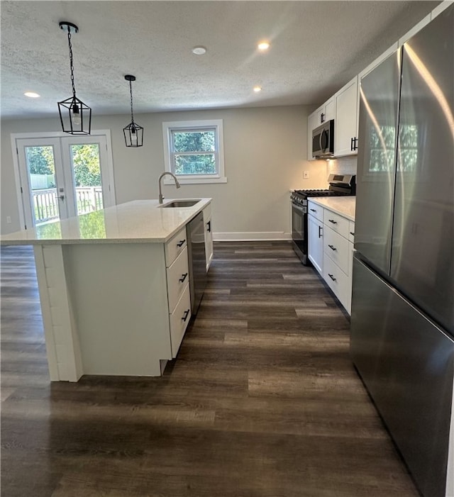 kitchen featuring white cabinets, appliances with stainless steel finishes, a healthy amount of sunlight, and decorative light fixtures