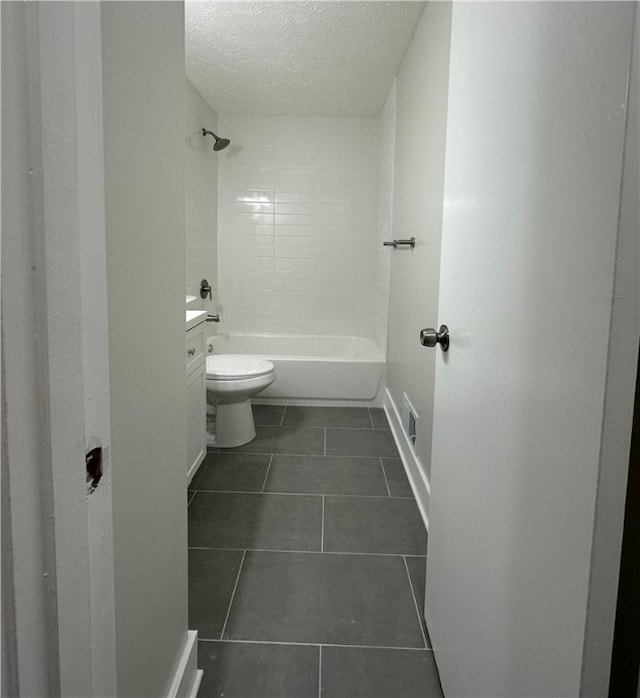 full bathroom featuring toilet, tile patterned floors, tiled shower / bath, a textured ceiling, and vanity