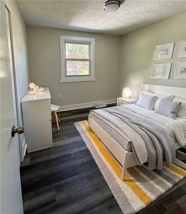 bedroom featuring a textured ceiling and dark hardwood / wood-style floors