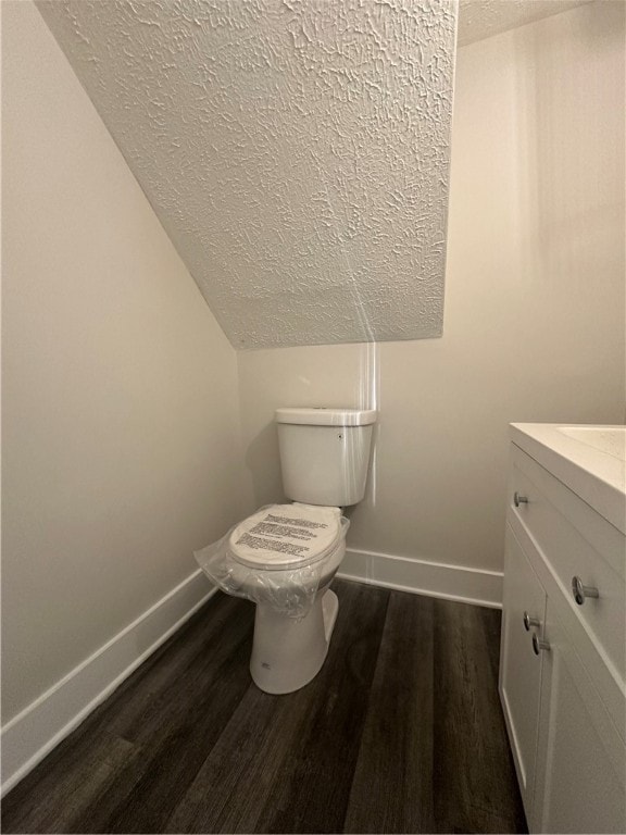 bathroom featuring toilet, vaulted ceiling, hardwood / wood-style floors, a textured ceiling, and vanity