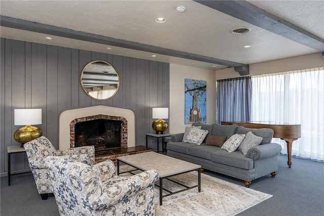 living room featuring carpet flooring, a brick fireplace, wood walls, and beam ceiling