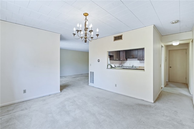 unfurnished living room with light carpet, an inviting chandelier, and ornamental molding