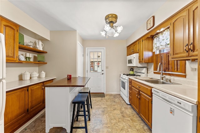 kitchen with a chandelier, white appliances, a breakfast bar area, and sink