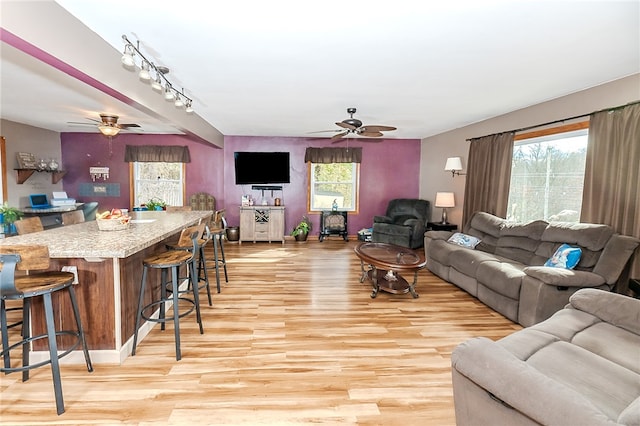 living room with a wealth of natural light, light hardwood / wood-style floors, and ceiling fan