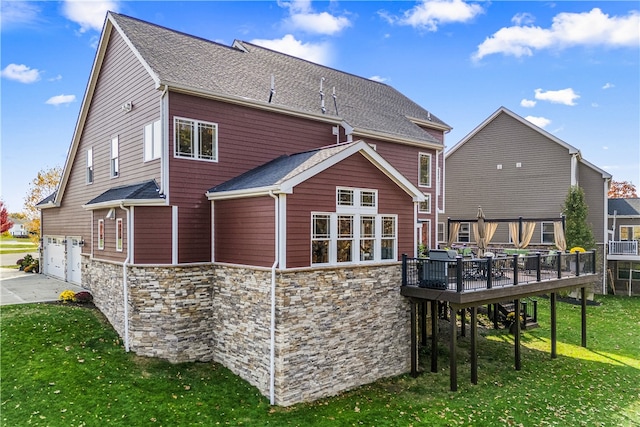 back of property featuring a deck, a garage, and a yard