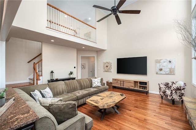 living room featuring a towering ceiling, ceiling fan, and hardwood / wood-style flooring