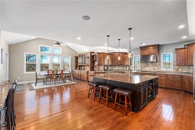 kitchen with backsplash, dark hardwood / wood-style floors, a kitchen breakfast bar, lofted ceiling, and a spacious island