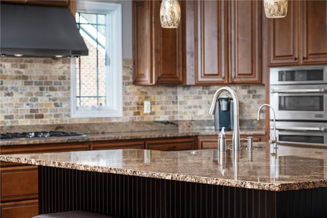 kitchen featuring decorative backsplash, appliances with stainless steel finishes, dark stone counters, and ventilation hood