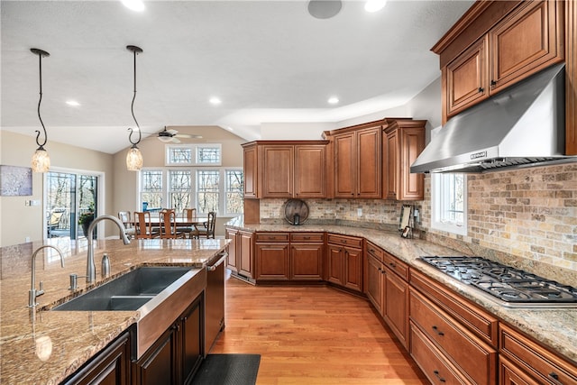 kitchen with stainless steel appliances, range hood, decorative light fixtures, decorative backsplash, and light hardwood / wood-style floors