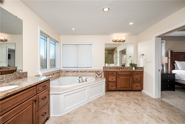 bathroom with plus walk in shower, vanity, a textured ceiling, and tile patterned flooring