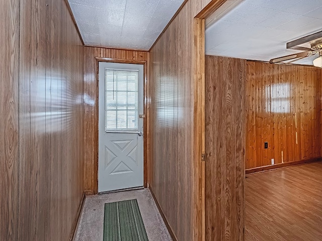 doorway with light wood-type flooring and wood walls