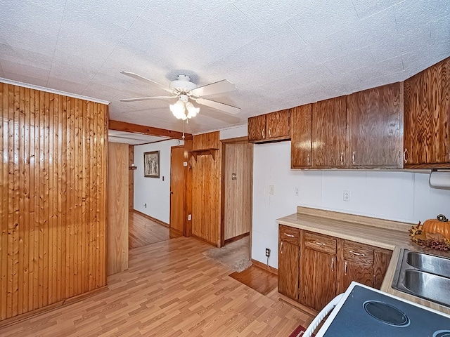 kitchen featuring wood walls, ceiling fan, a textured ceiling, and light wood-type flooring