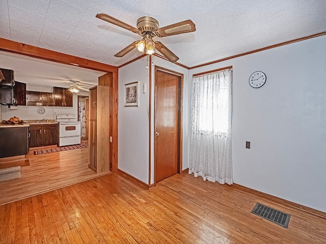 unfurnished living room featuring ceiling fan, a textured ceiling, light hardwood / wood-style floors, and crown molding