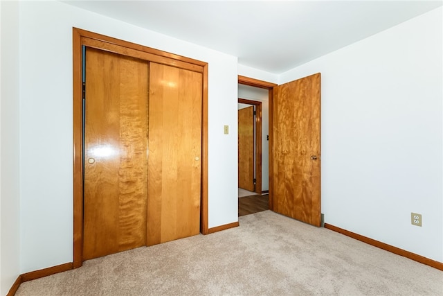 unfurnished bedroom featuring light carpet and a closet