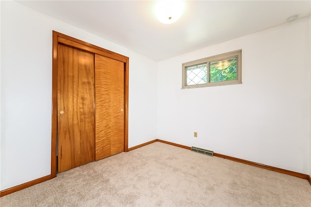 unfurnished bedroom featuring light colored carpet and a closet