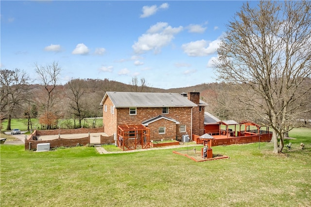 rear view of property featuring a wooden deck, a yard, and central AC