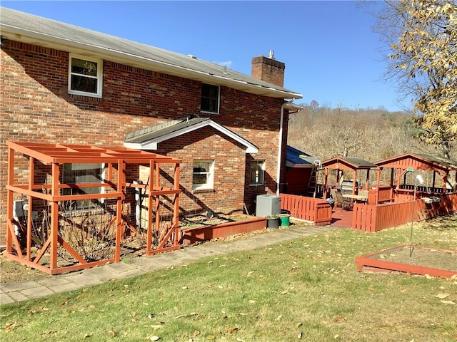 rear view of property featuring a wooden deck and a yard