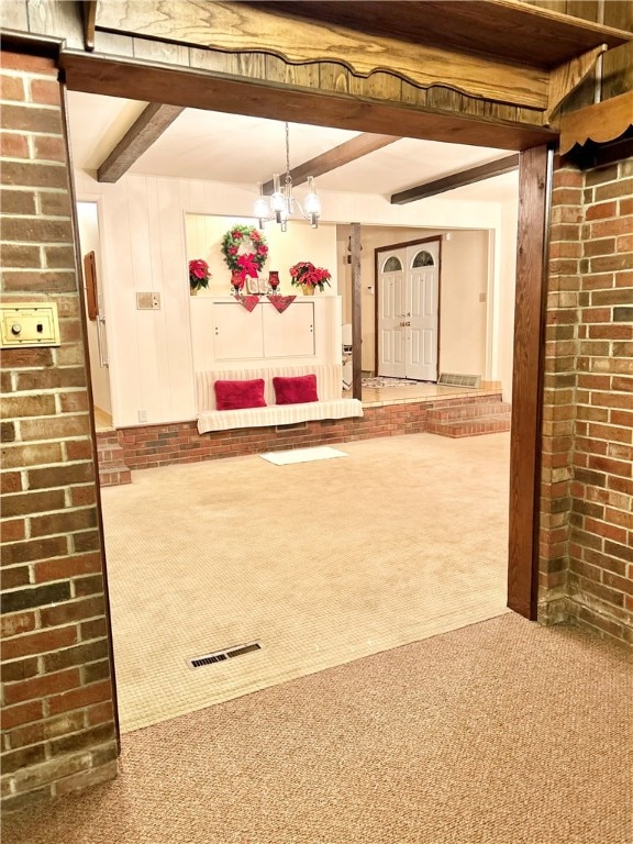 interior space with beam ceiling, carpet, and an inviting chandelier