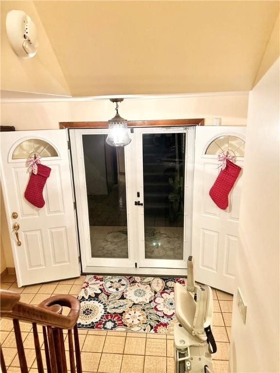 doorway with light tile patterned flooring and vaulted ceiling