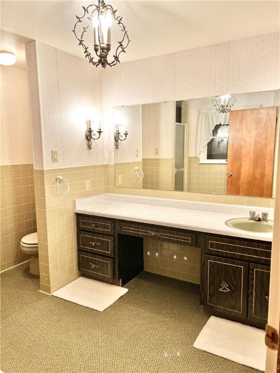 bathroom featuring a notable chandelier, vanity, tile walls, and toilet