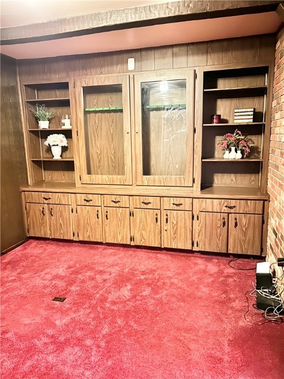 unfurnished living room with carpet flooring, built in shelves, and wooden walls