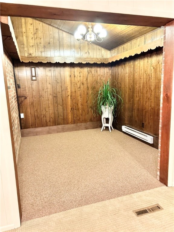 empty room with carpet, an inviting chandelier, a baseboard heating unit, wooden walls, and beamed ceiling